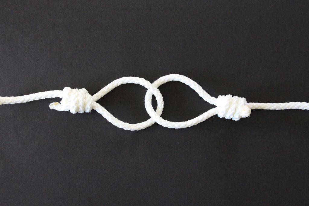 A photo of a rope tied as a slip knot and it is hanging another slip knot.